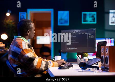 Black software engineer writes complex binary code scripts on computer, cybersecurity. Teleworking IT specialist in home office using programming language to safeguard consumer data. Stock Photo