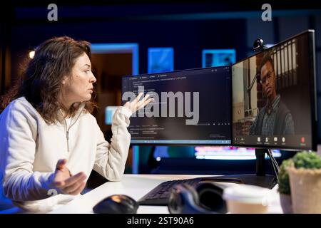 Software technician teacher doing online tutoring, talking with student in online videocall about ways to do debugging. IT master teaching apprentice woman in webinar how to write code Stock Photo
