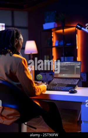 Technician in home office typing code on notebook device, developing software programs, entering commands. Skillful gen Z teenager at home fixing errors in application, implementing new features Stock Photo