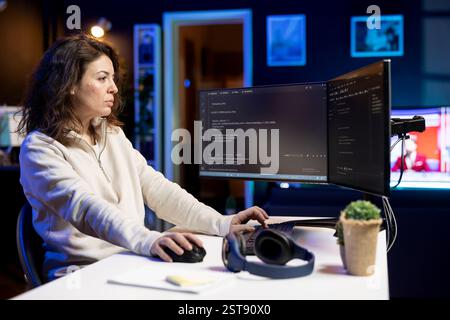 Computer scientist doing software debugging on PC at home, checking broken lines of code displayed on monitors. Skilled IT expert in apartment fixing coding problems, typing on keyboard Stock Photo