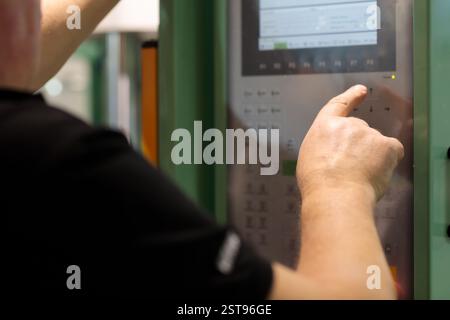 Operator controls machine with the control panel. Operator of plastic injection molding machine at work. Modern industrial manufacturing concept. Sele Stock Photo