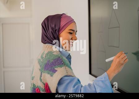 A Business Arab woman mentor leading team training workshop or a Muslim female student answering at the smart board or presenting project or teacher Stock Photo