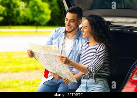 Loving middle-eastern couple watching map while having break, copy space Stock Photo