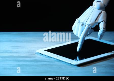 Artificial intelligence. Robot hand using tablet at wooden table, closeup. Space for text Stock Photo