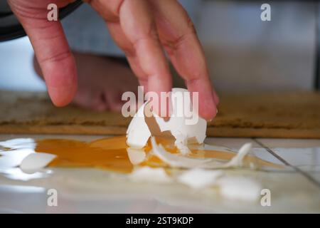 Egg shell cracks on kitchen floor after accidental drop during cooking Stock Photo
