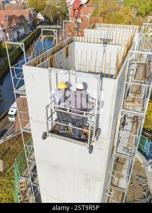 Construction workers on a lifting platform on a large concrete tower by a river, extension of the Calw railway station for the new track of the Herman Stock Photo