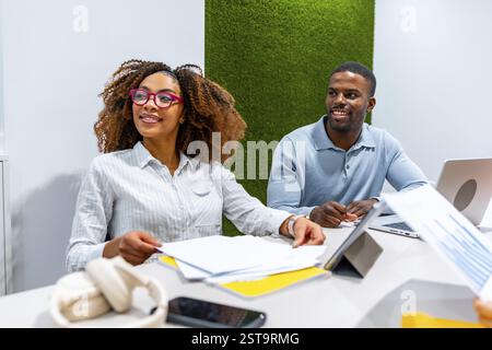 Two managers are cooperating in a modern coworking office, analyzing financial reports and discussing company strategies Stock Photo