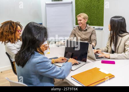 Multi ethnic business team collaborating on project in modern coworking office, using laptops and discussing ideas Stock Photo