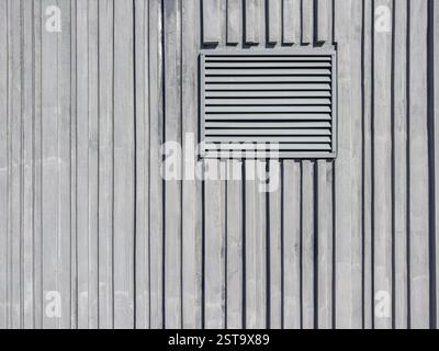 metal lattice of a technical window of ventilation on a gray ridge concrete wall. Stock Photo