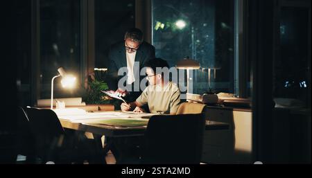 Night, meeting and tablet for feedback, teamwork and overtime work for data analysis. Business men, mentor programmer and collaboration for web design Stock Photo