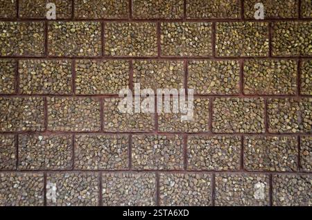 Textured brown exposed aggregate stone block wall texture pattern background. Stock Photo