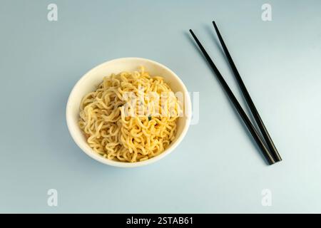 Concept of tasty eating with bowl of noodles on blue background. Instant noodles, bright blue background color. Stock Photo