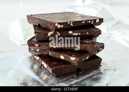 broken chocolate and hazelnuts on white wooden table. broken chocolate slices. Stock Photo
