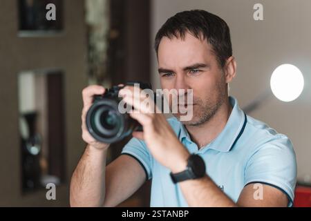 The man use the professional camera with telephoto lens. Close up photo of man in hat on gray background taking a photo with digital mirrorless camera Stock Photo
