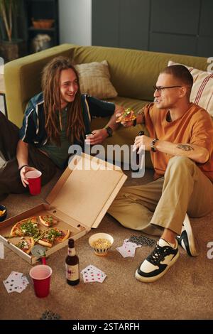 Enjoying Pizza and Drinks while Having Fun with Cards Stock Photo