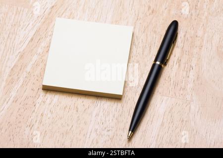 Pen and Post It Notes Pad Against a Wood Background Stock Photo