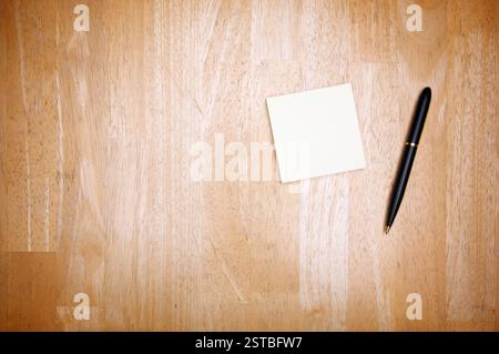 Pen and Post It Notes Pad Against a Wood Background Stock Photo