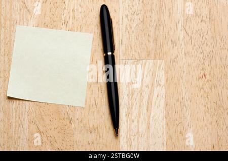 Pen and Post It Notes Pad Against a Wood Background Stock Photo