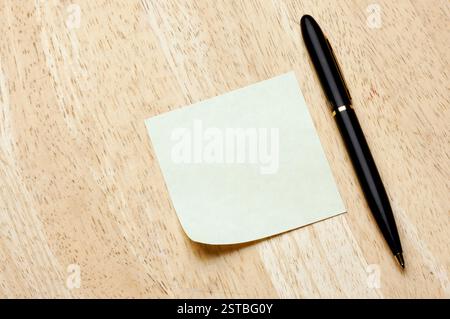 Pen and Post It Notes Pad Against a Wood Background Stock Photo