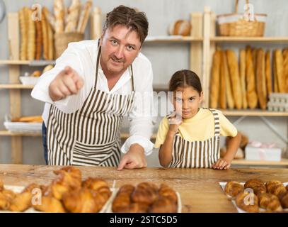 Uncle and girl are laughing, having fun, doing prank in trading floor of bakery store Stock Photo