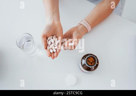 Top view of woman's hands that holding pills. Professional medical worker in white coat is in the office. Stock Photo