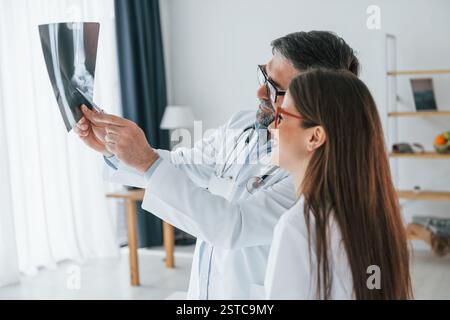 Looking at x-ray. Professional medical workers in white coats is in the office. Stock Photo