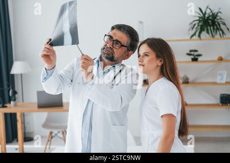 Looking at x-ray. Professional medical workers in white coats is in the office. Stock Photo