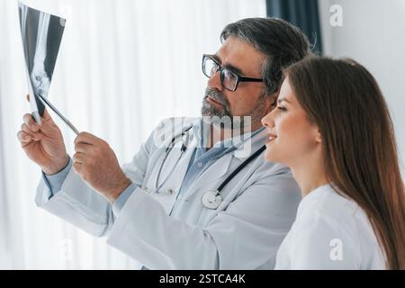 Traumatic picture on the x-ray. Professional medical workers in white coats is in the office. Stock Photo