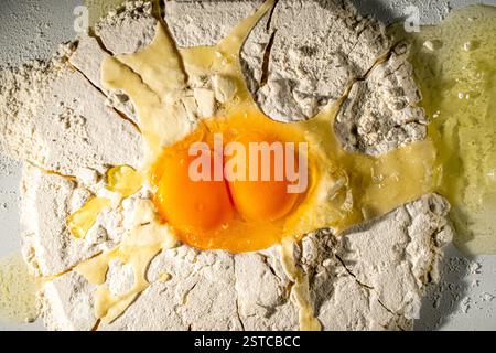 Two chicken eggs are broken in flour to make dough. Close-up. High quality photo Stock Photo