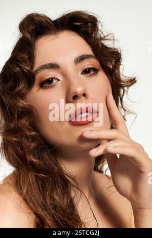 A captivating young woman with curly hair poses gracefully in bright light. Stock Photo