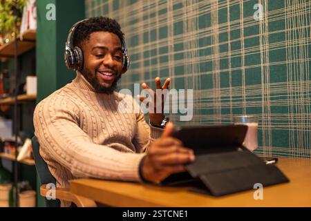 Freelancer using digital tablet to communicate online. He is sitting in bar and having video call. Stock Photo