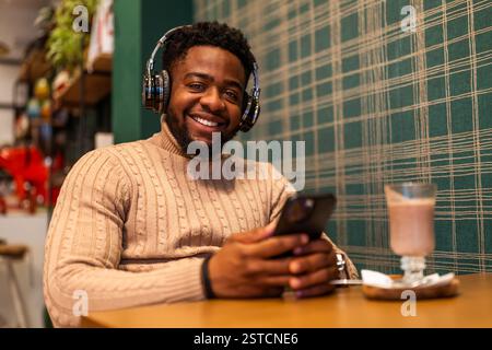 Freelancer is having pause from work, he is using smartphone and drinking hot chocolate in bar. Stock Photo