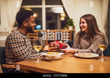 Two friends are having dinner at restaurant. They are exchanging gifts. Stock Photo