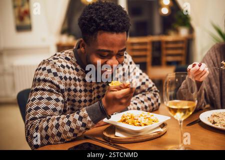 Happy young black man is having dinner and wine at restaurant. Stock Photo