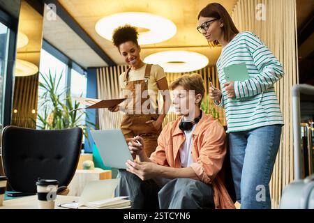 Colleagues engage in discussions while working on a laptop in a stylish hotel environment. Stock Photo