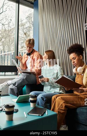 Three colleagues collaborate in a stylish hotel lounge, focusing on their tasks with enthusiasm. Stock Photo