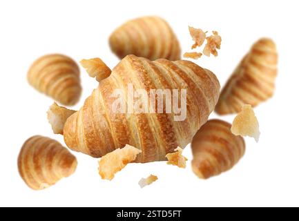 Delicious croissants and crumbs in air on white background. Puff pastry Stock Photo