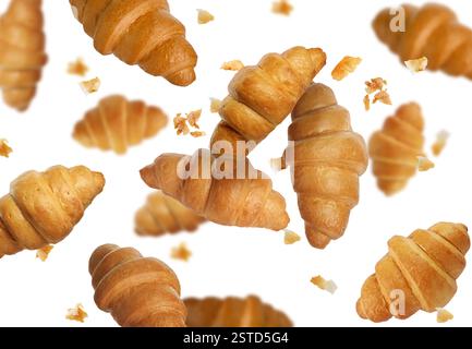 Delicious croissants and crumbs in air on white background. Puff pastry Stock Photo