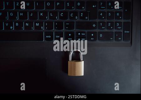 A golden padlock rests on a black laptop keyboard, symbolizing online security, data protection, and digital privacy in the modern world. Stock Photo