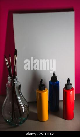 Creative art supplies and a blank canvas arranged on a table against a vibrant background for an artistic project Stock Photo