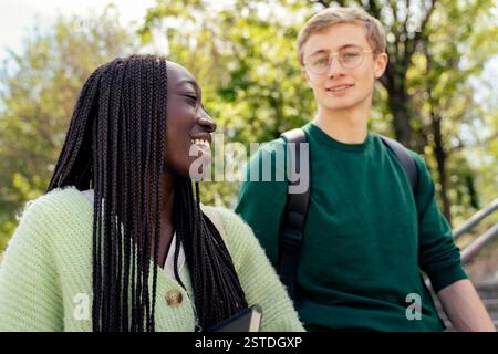Two students sharing a joyful moment in a green university campus. A great representation of student friendships and well-being in academic life. Stock Photo