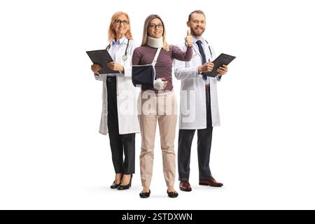 Woman recivering after surgery and gesturing thumbs up with a team of doctors isolated on white background Stock Photo