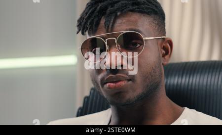 Portrait serious stylish fashionable African American cyber man in white futurism studio male guy futuristic fashion style wearing sunglasses Stock Photo
