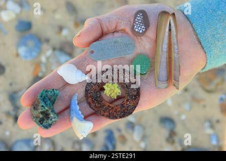 Beach combing treasures found on a English beach including sea glass, shells, an identity tag and interesting pebbles. England, UK Stock Photo