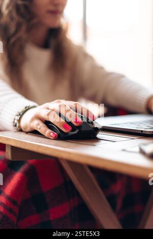 Anonymous of young female freelancer sitting at table with laptop and typing information while working on new project in modern home Stock Photo