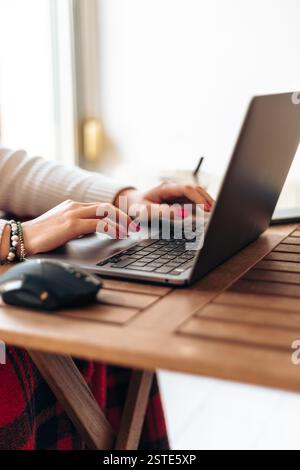 Crop faceless female freelancer typing on laptop while working on freelance project remotely at home Stock Photo