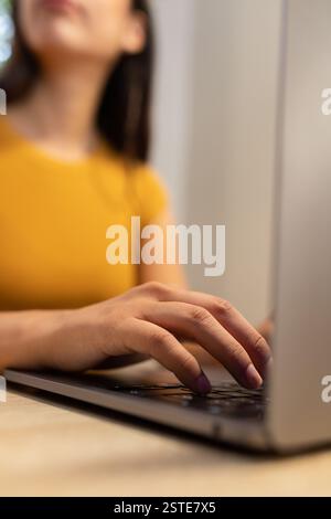 Cropped unrecognizable young female entrepreneur sitting at table and browsing netbook while working on modern workplace Stock Photo