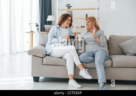 With cup of drinks, having a conversation. Mother and daughter is together at home. Stock Photo