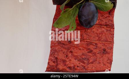 Plum pastille or fruit leather on a white background. Blurred plum. Copy space. Stock Photo