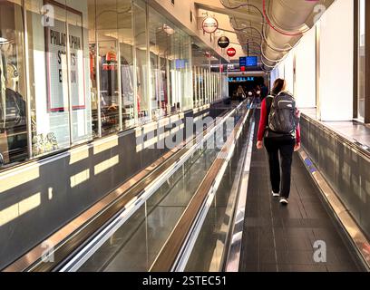 Woman walks to her gate with the assistence of a conveyor belt. Stock Photo